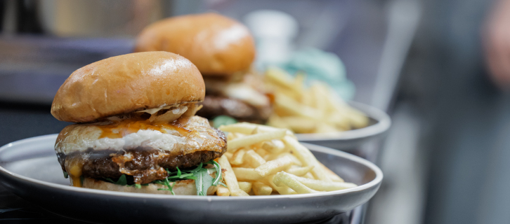Saftiger Burger mit Pommes auf einem Teller, servierbereit in der Küche.