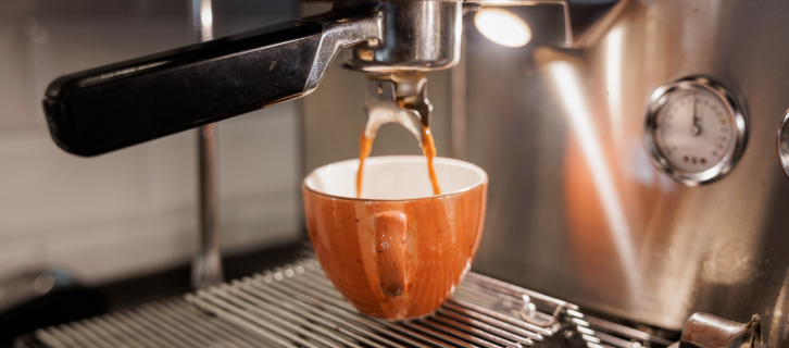 Espressomaschine in Nahaufnahme, aus der frisch gebrühter Kaffee in eine Tasse fließt.