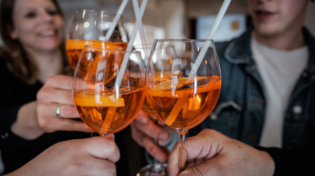 Mehrere Personen stoßen mit Aperitifgläsern an.